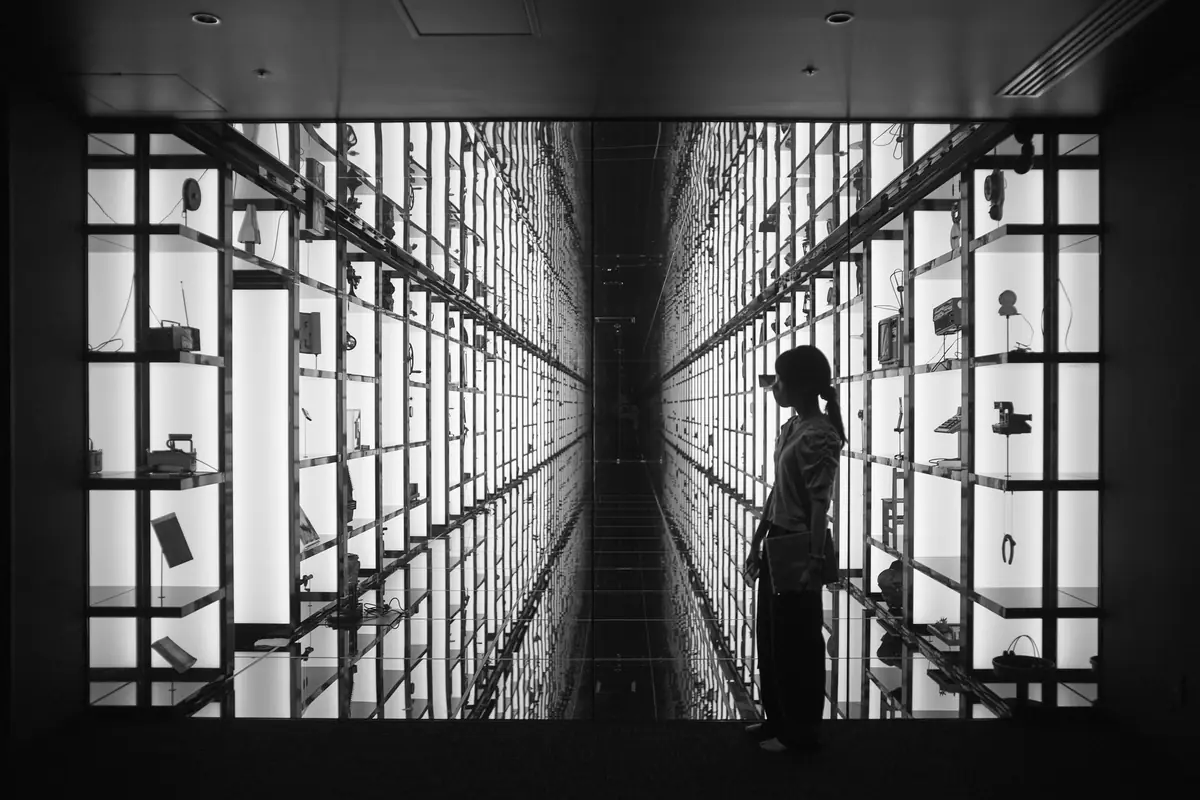 A silhouette before glowing shelves stretching to infinity