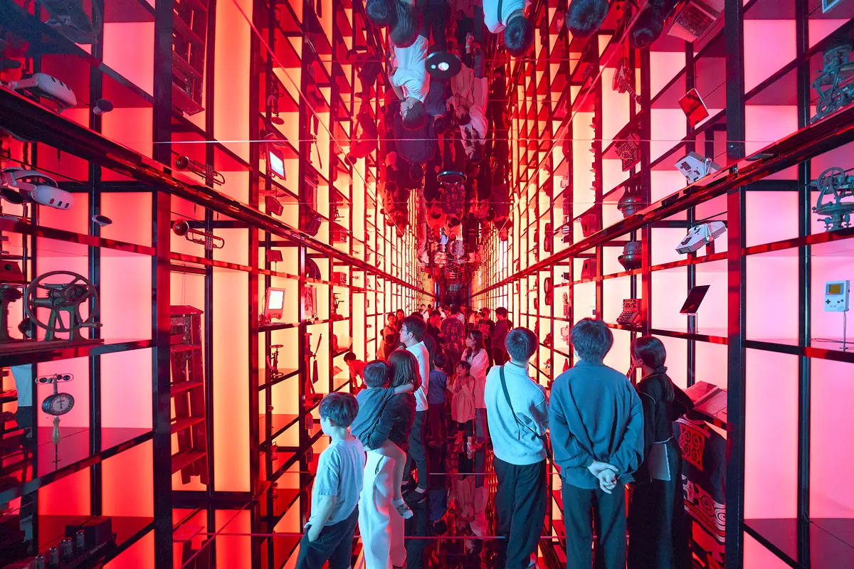 Shelves of objects and visitors bathed in red light